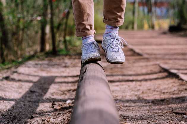 Photo of person balancing on a log of wood